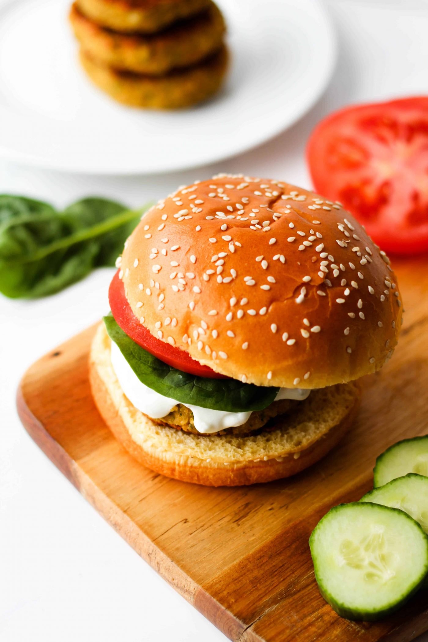greek chickpea burger on a bun with lettuce, tomato and tzatziki