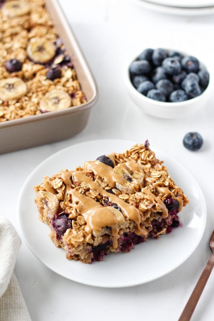 Vegan baked oatmeal with blueberries and bananas on a plate drizzled with peanut butter