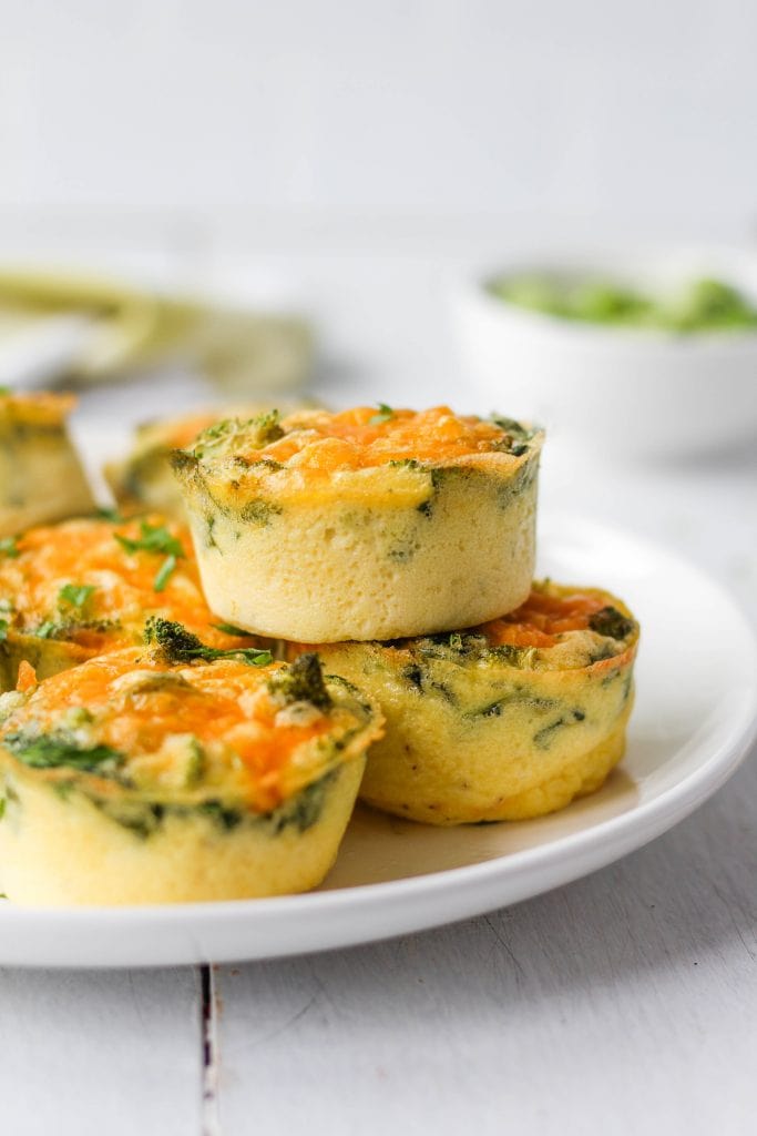 Broccoli cheddar baked egg bites stacked on a white plate.