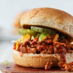 Ground chicken sloppy joes on a bun with cheese, lettuce and pickles.