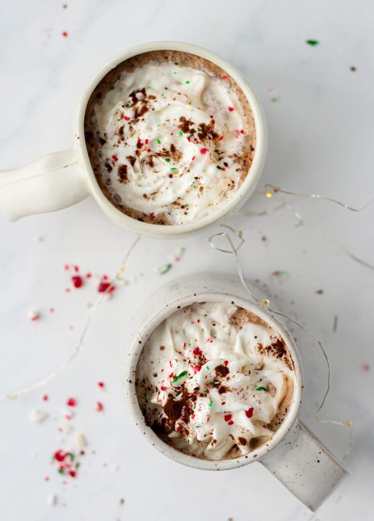 Two peppermint mochas in white mugs with whipped cream on top.