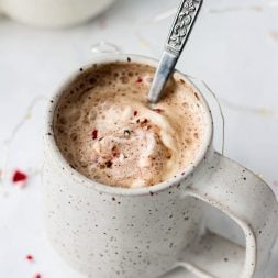 Latte in a speckled white mug on a white marble surface