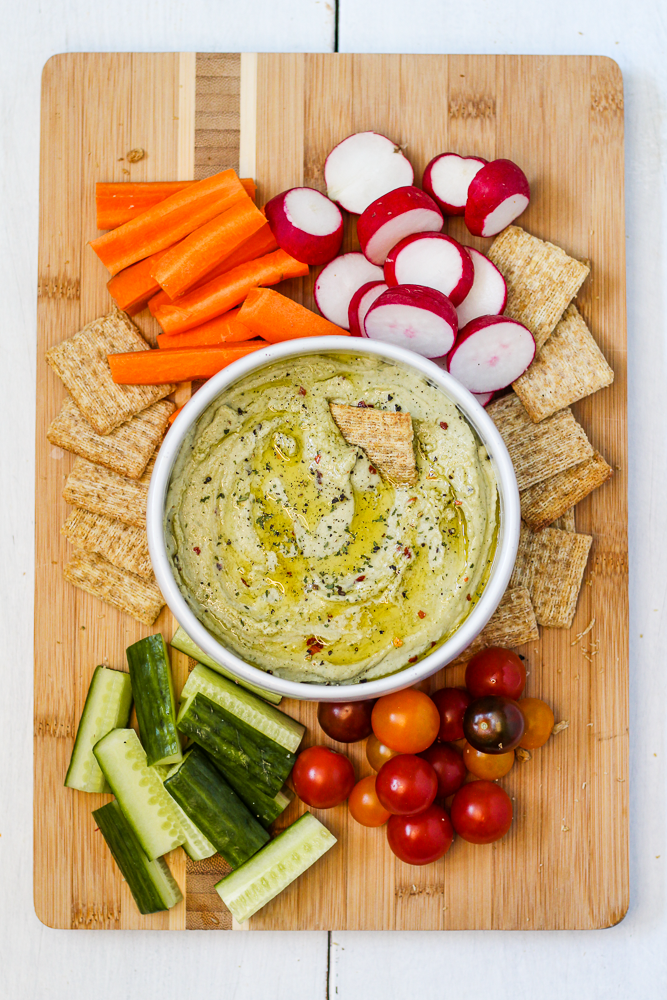 white bean dip on a board with vegetables and crackers