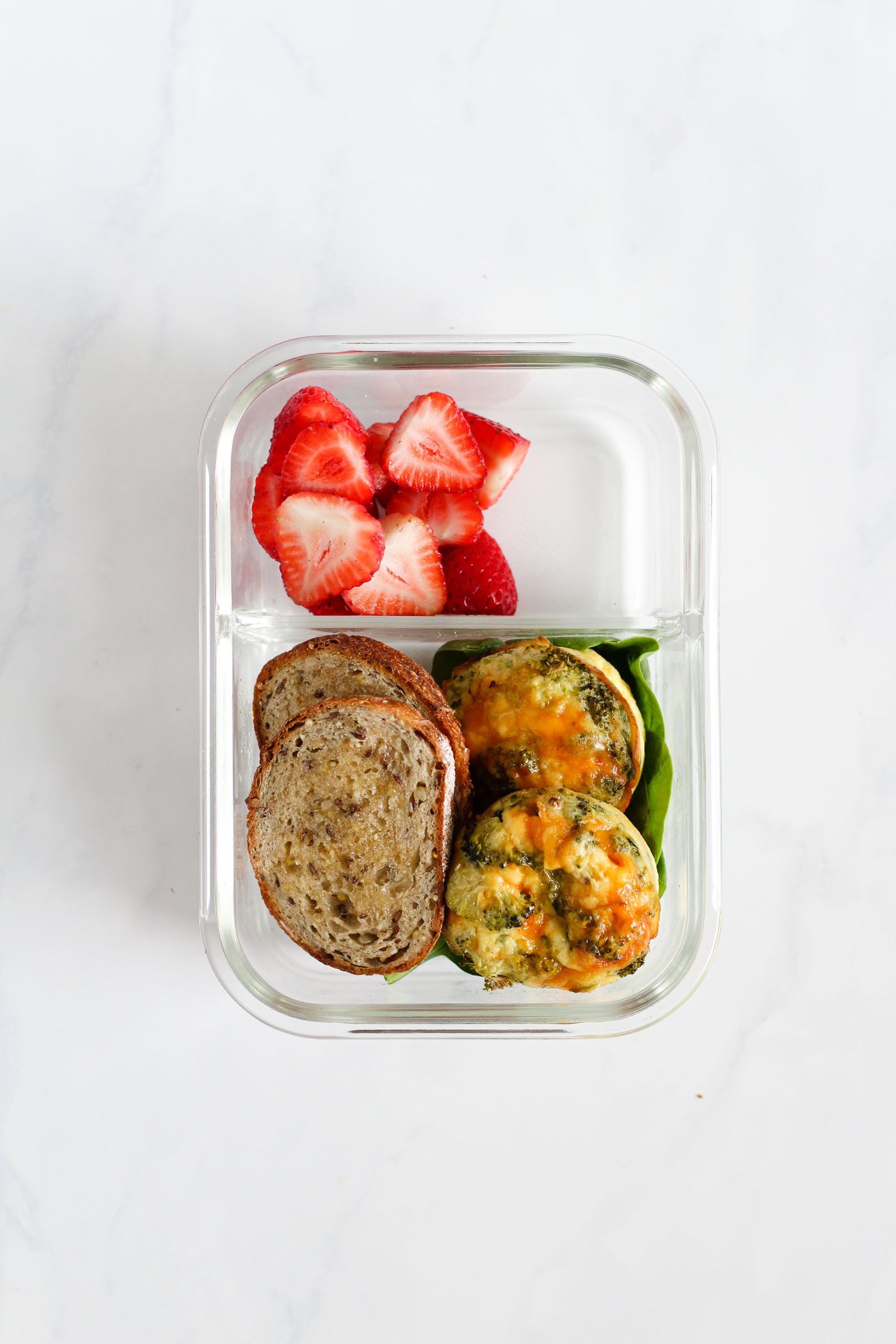 lunch box with egg bites, toast, spinach and strawberries