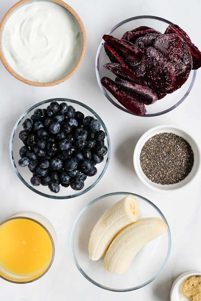 ingredients for a beet smoothie including greek yogurt, frozen beets, blueberries, banana, chia seeds and orange juice