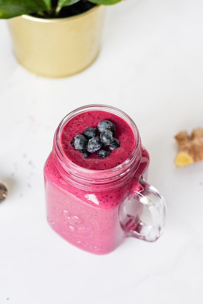 red beetroot smoothie in a mason jar with blueberries on top