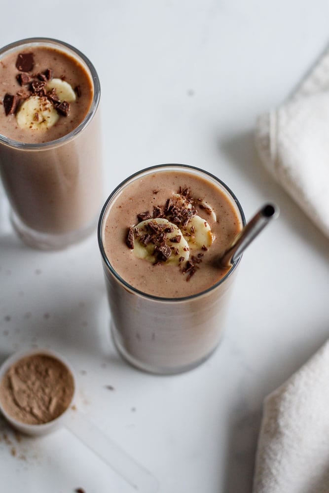 chocolate cauliflower smoothies in glasses topped with sliced banana and chopped up chocolate