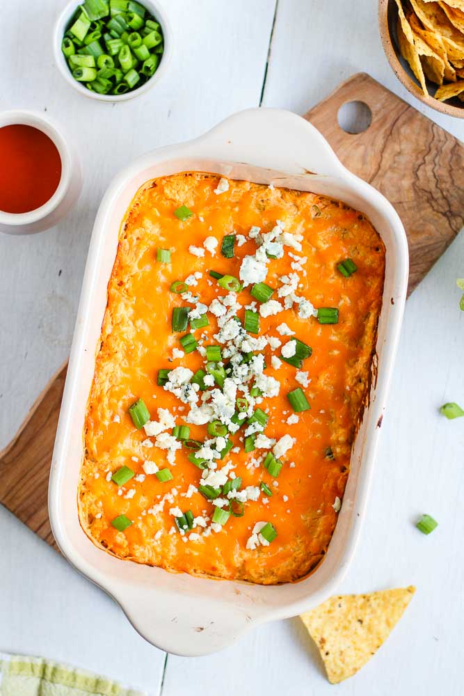 buffalo chicken dip topped with blue cheese and green onion served in a baking dish