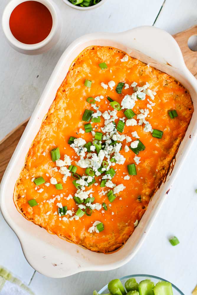 buffalo chicken dip topped with blue cheese and green onion served in a baking dish