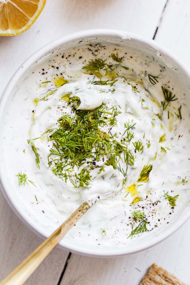 homemade tzatziki sauce in a bowl garnished with fresh dill and olive oil