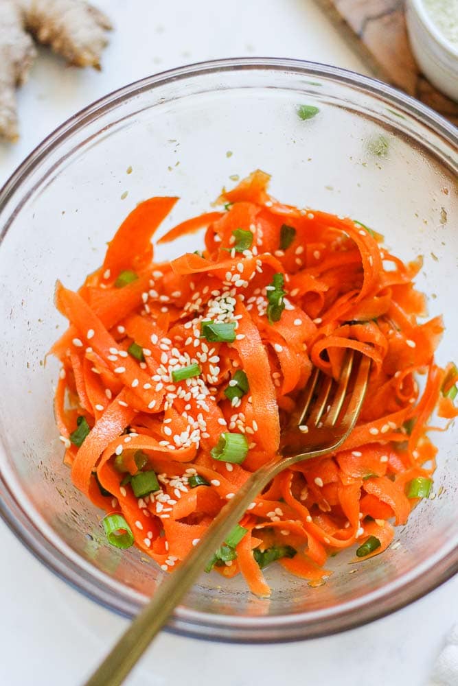raw carrot salad in a bowl with a fork