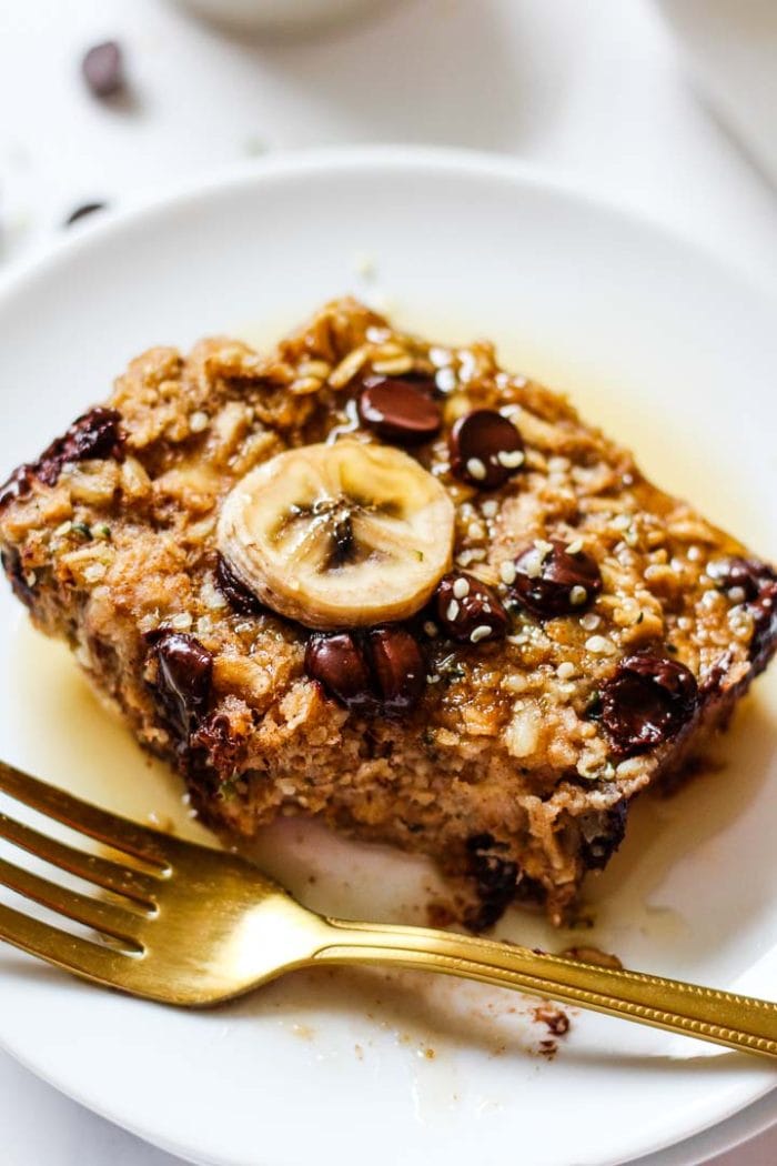 slice of baked oatmeal topped with a banana slice, chocolate chips, and maple syrup
