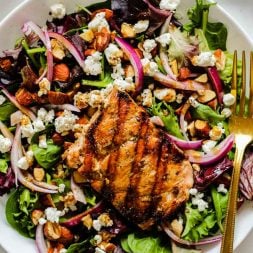 grilled salmon on a salad with spring mix, red onion, almonds, goat cheese, and cranberries