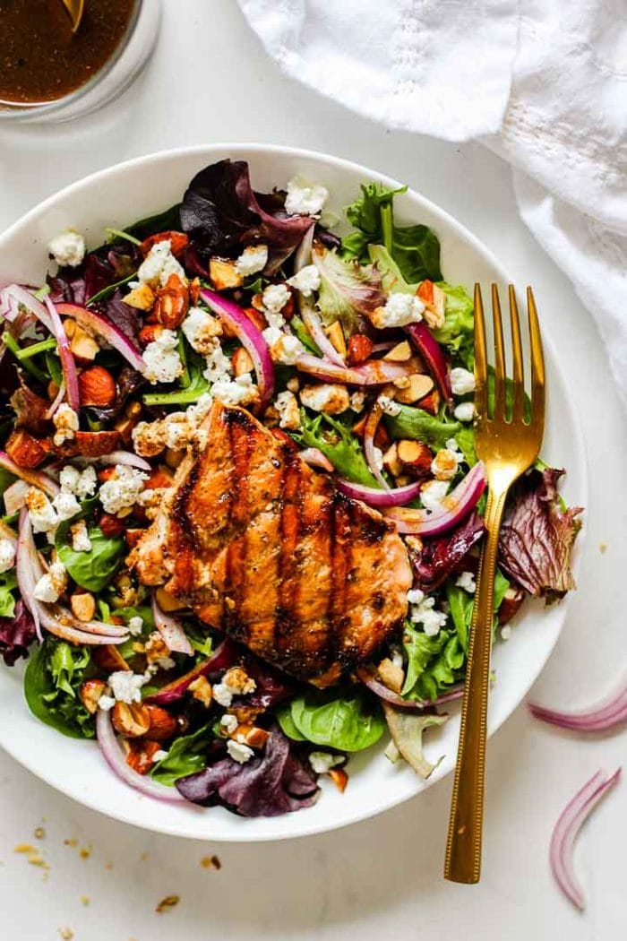 grilled salmon on a salad with spring mix, red onion, almonds, goat cheese, and cranberries