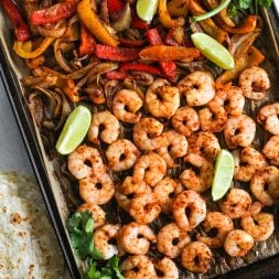 shrimp, peppers and onions cooked with fajita seasoning on a sheet pan