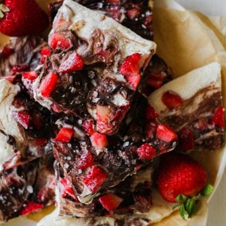 pieces of greek yogurt bark with chocolate and strawberries layered on a plate