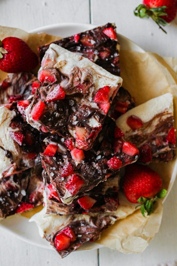 pieces of greek yogurt bark with chocolate and strawberries layered on a plate