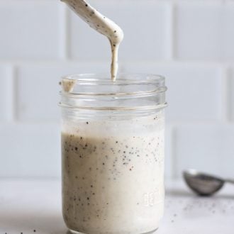 spoon dripping with poppyseed dressing over a jar of the dressing