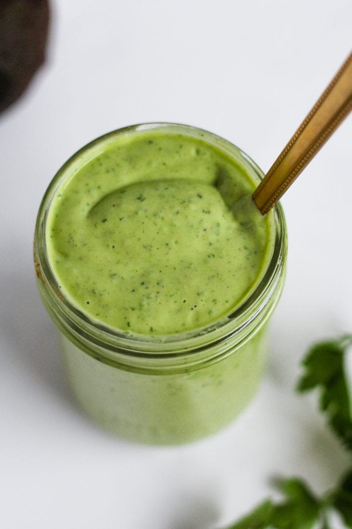 spoon in a jar of green greek yogurt avocado salad dressing