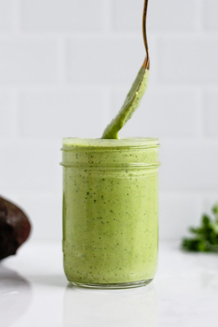 spoon in a jar of green greek yogurt avocado salad dressing 