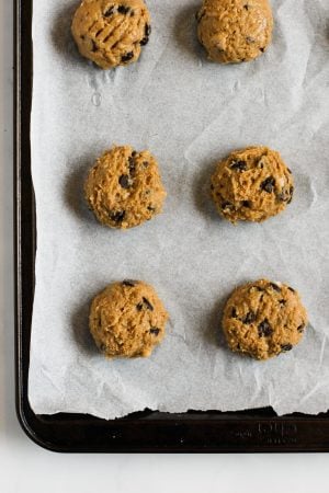 Cookie dough scooped out onto a baking sheet lined with parchment paper