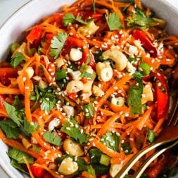 bowl of salad made with shredded carrots, sliced red bell pepper, cilantro, green onion, and cashews