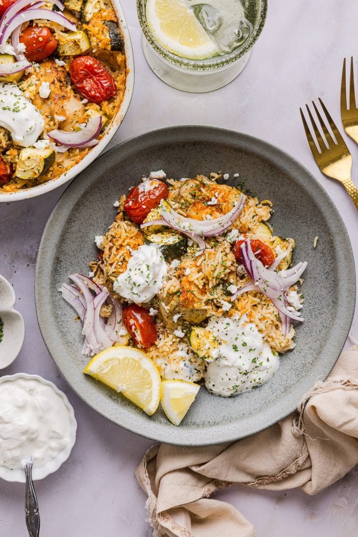 greek chicken and rice casserole served in a bowl and topped with sliced red onion and feta cheese
