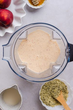 blended peach smoothie in a blender container
